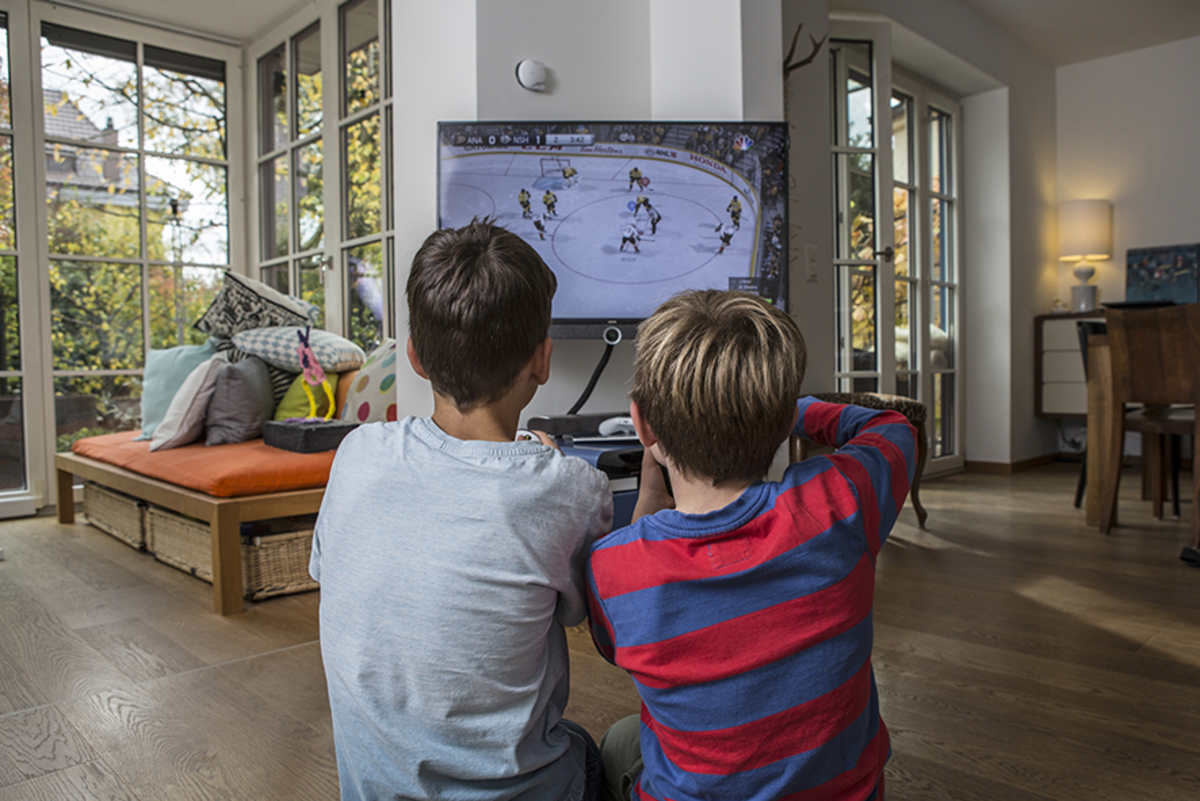 Due bambini che giocano insieme una partita di hockey su ghiaccio alla TV.
