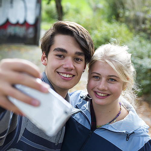 Un ragazzo e una ragazza scattano una foto insieme con il cellulare. 