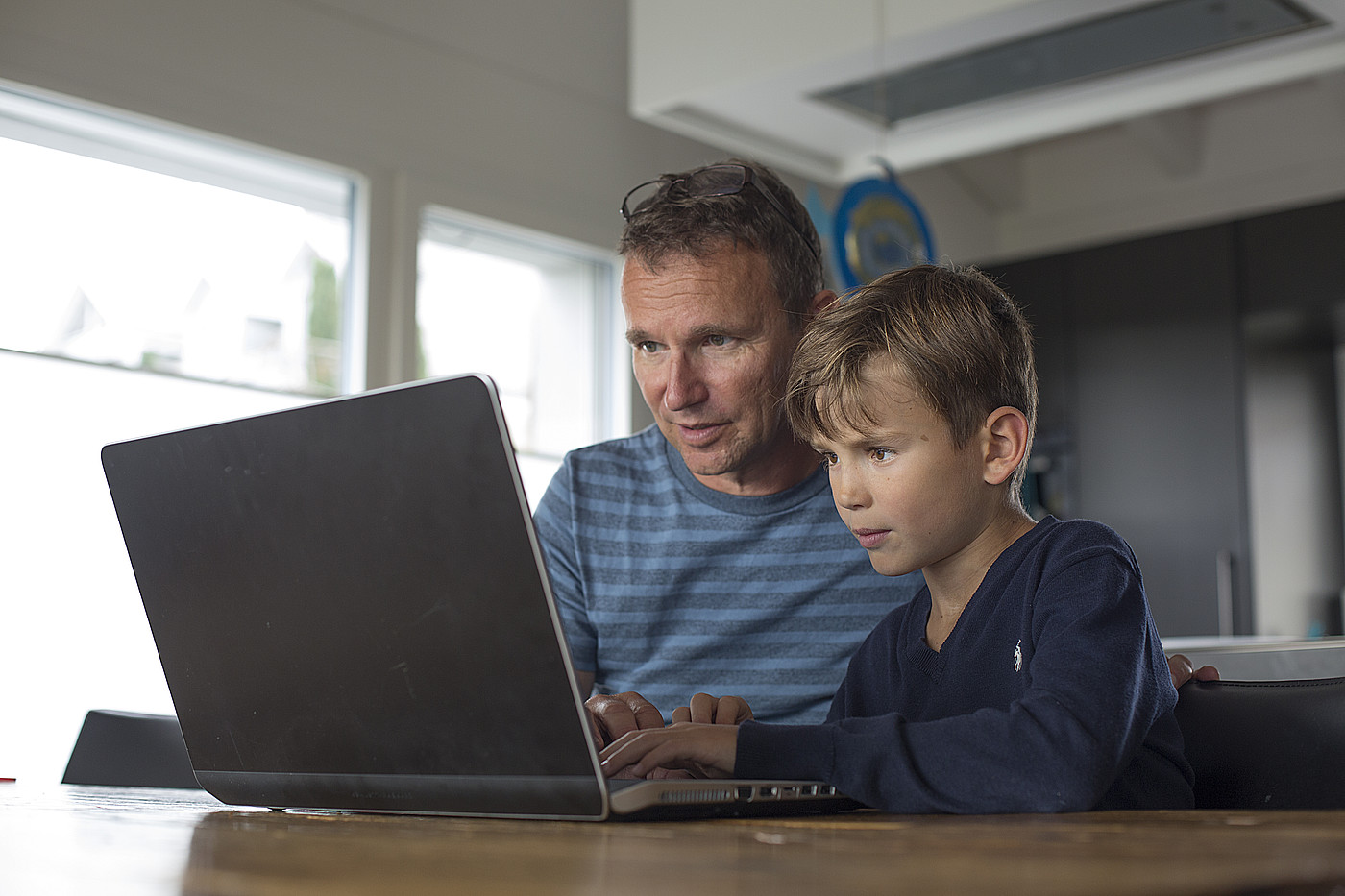 Un padre e un bambino che guardano insieme un computer portatile.