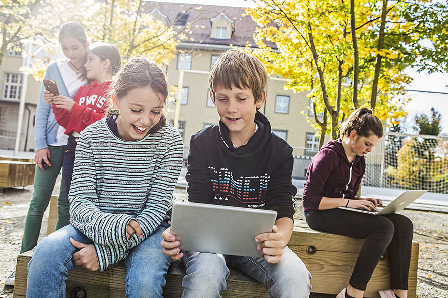 Gli alunni usano i dispositivi mobili nel cortile della scuola.