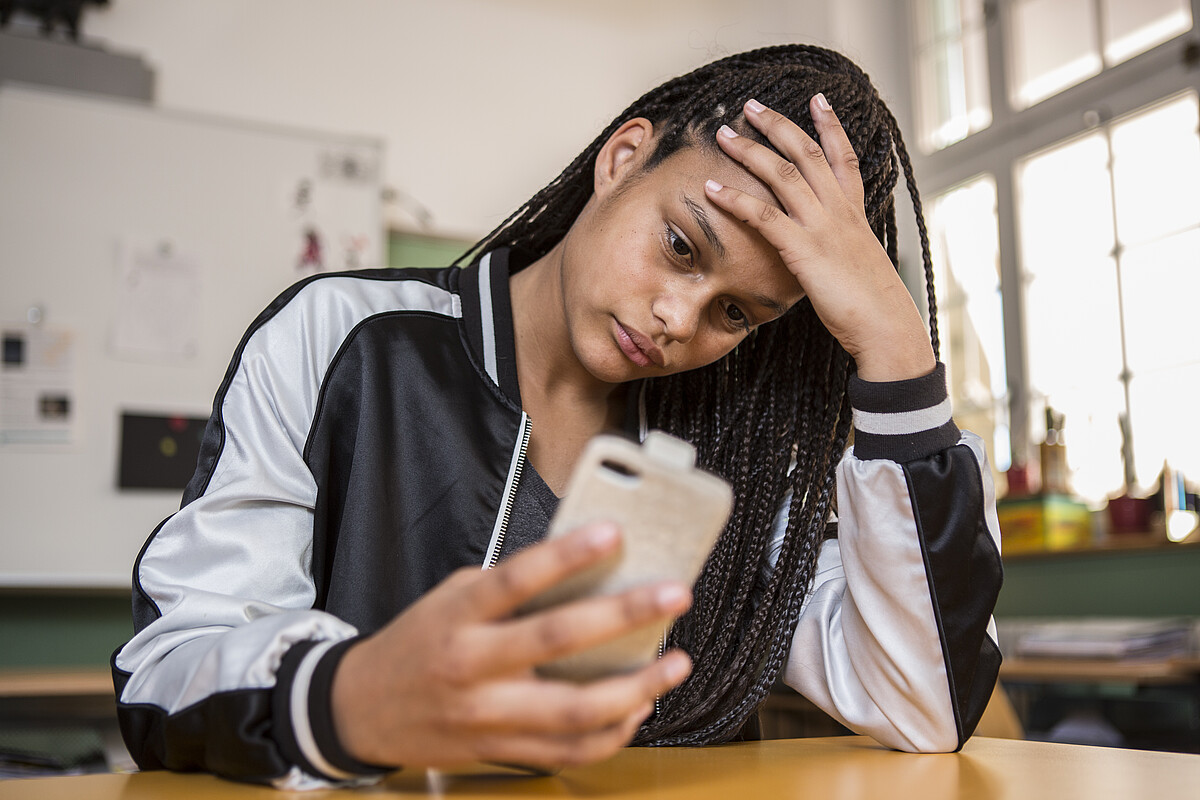 Un'adolescente angosciata è seduta al suo cellulare.