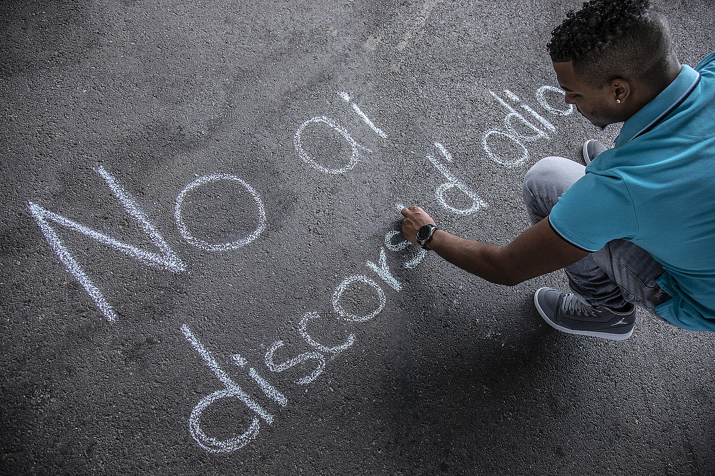 Un adolescente che scrive qualcosa sul pavimento con il gesso