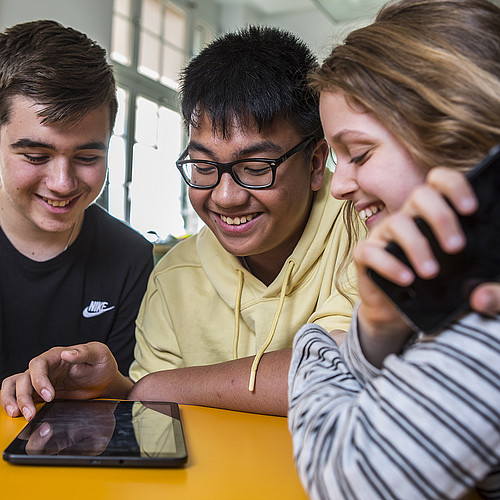 Giovani felici che usano i loro telefoni cellulari in classe.