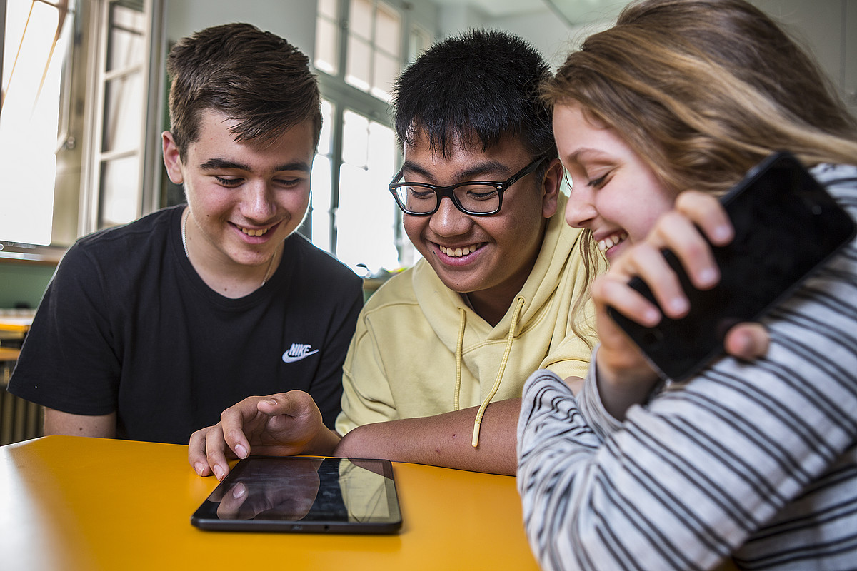 Giovani felici che usano i loro telefoni cellulari in classe.