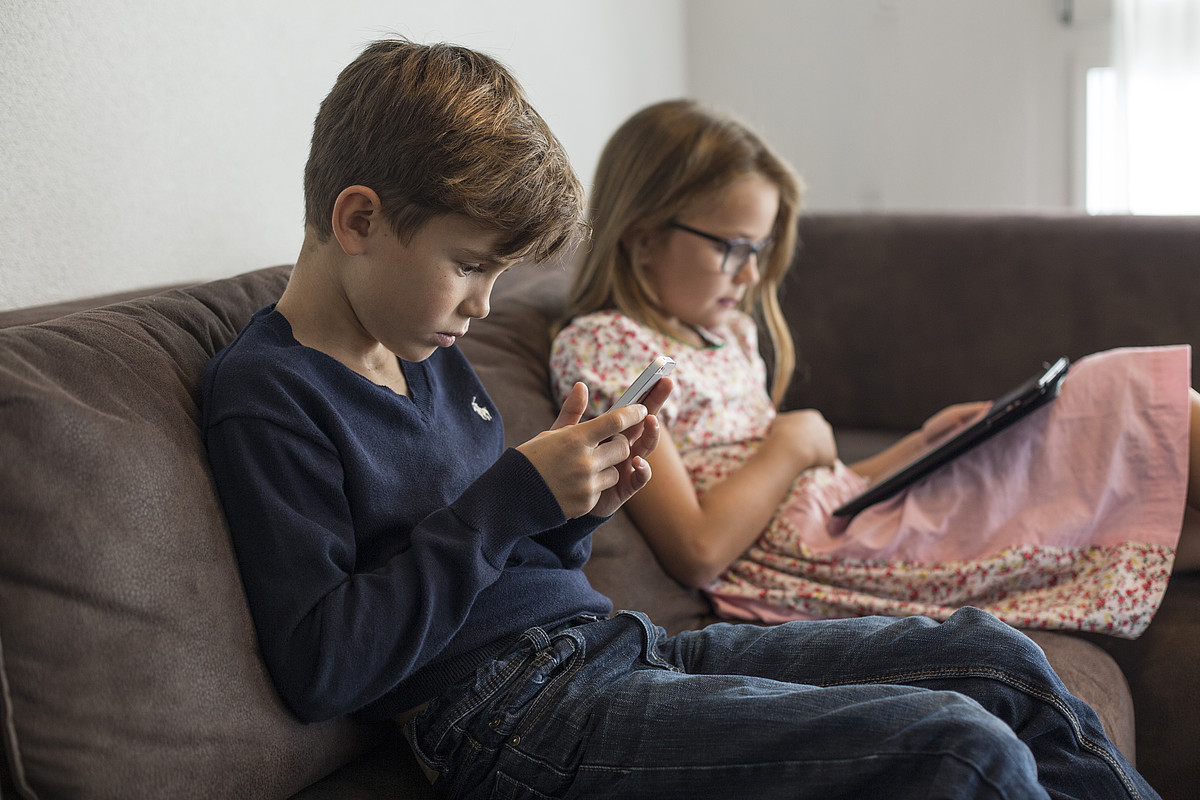 Due ragazzi seduti su un divano con uno smartphone o un tablet in mano.