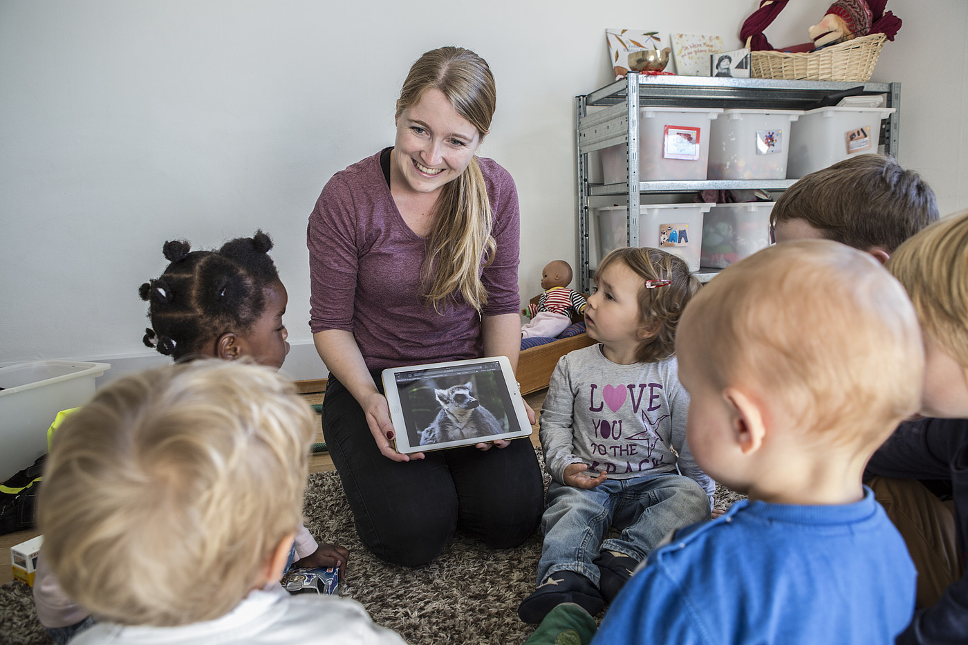 Una bambinaia che dice qualcosa ai bambini con il tablet.