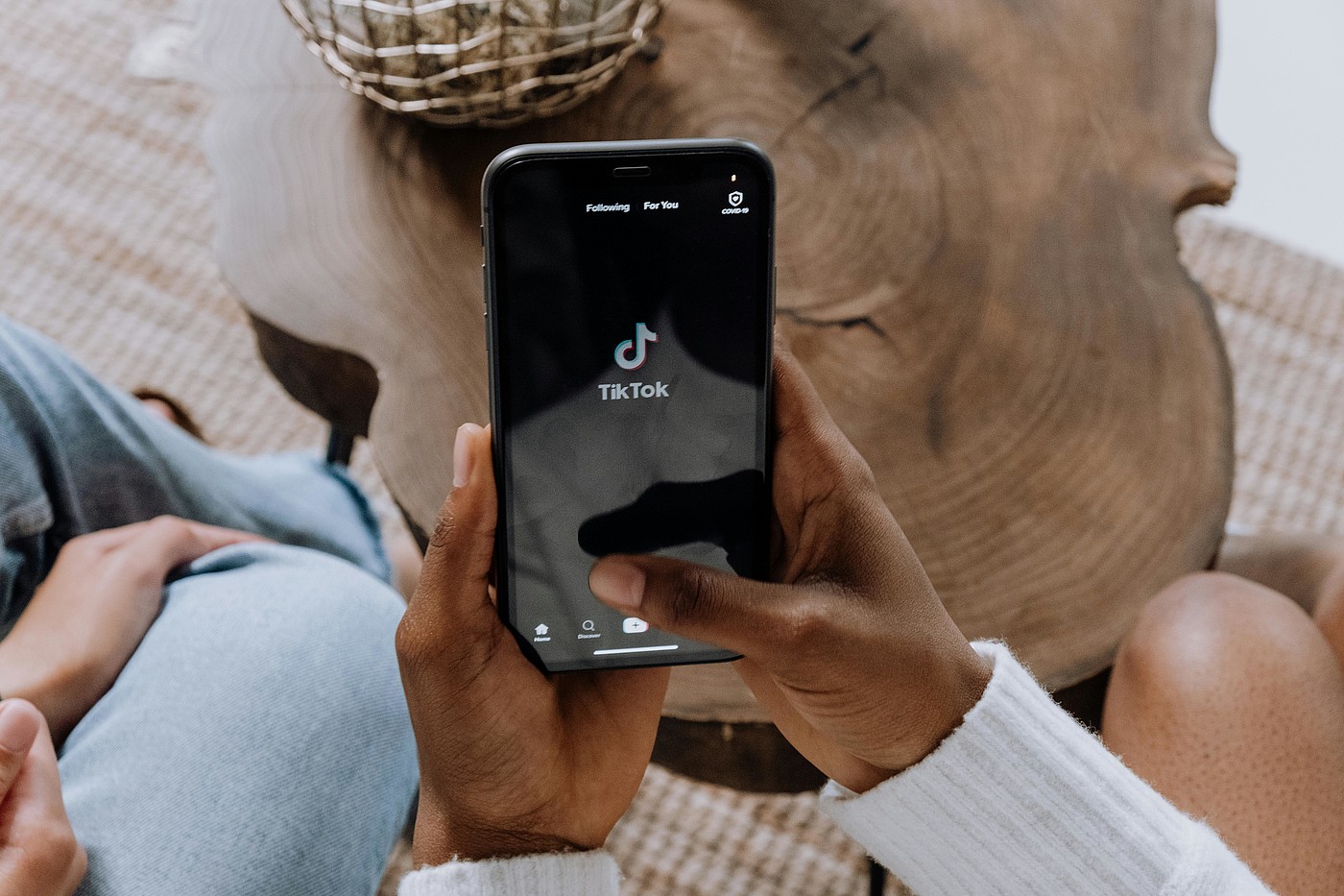 Due persone si siedono una accanto all'altra, una di loro tiene in mano uno smartphone con il logo TikTok sopra