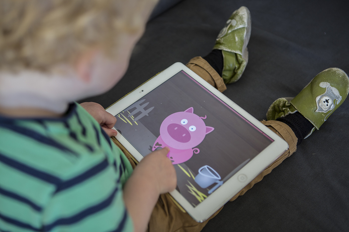 Un bambino sta guardando qualcosa sul tablet. C'è un maiale animato sul tablet.