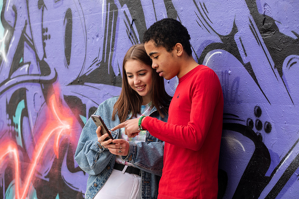 Due adolescenti che guardano insieme uno smartphone.